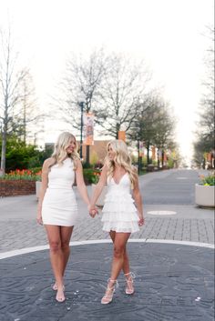 two women in white dresses holding hands