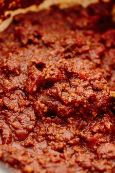 a bowl filled with red sauce on top of a wooden spoon