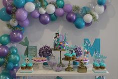 a table topped with lots of desserts and balloons