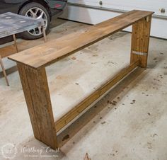 a wooden bench sitting in front of a garage door next to a table with wheels on it