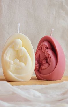 two carved soaps sitting next to each other on a wooden table with white sheets