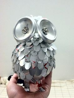 an owl made out of cans sitting on top of a bed