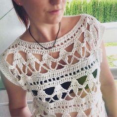 a woman wearing a white crochet top and black necklace