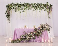 the table is set up with candles and greenery for an elegant wedding reception in lavender hues