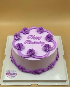 a birthday cake with purple icing on a white plate