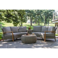 an outdoor furniture set on a patio with trees in the background and grass around it