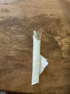 a fork and napkin sitting on top of a wooden table