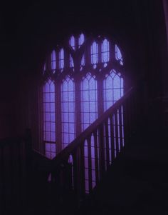 the stairs lead up to an arched window in a dark room with purple light coming through it