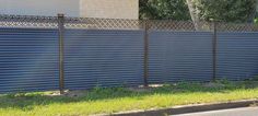 a fire hydrant sitting on the side of a road next to a tall fence