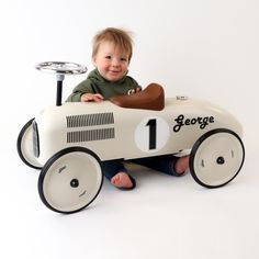 a little boy sitting in a toy race car with the number 1 on it's side