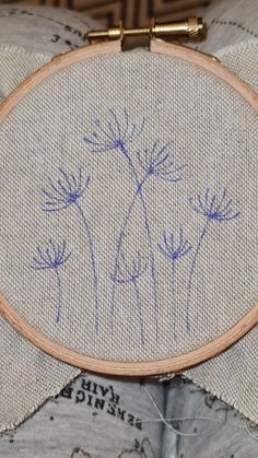 a close up of a cross stitch on a pillow with blue flowers in the middle