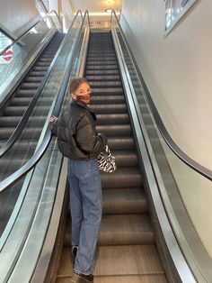 a woman is standing on an escalator with her hand in her pocket and looking up