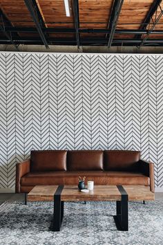 a brown leather couch sitting on top of a wooden table in front of a wall