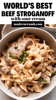 a bowl full of pasta with meat and sauce in it, on top of a white table