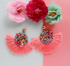 two pink flowers and some tassels on a table