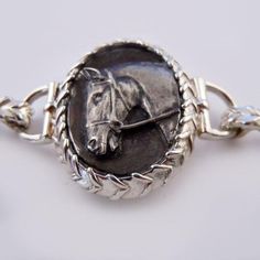 a silver bracelet with a horse head on it's side and a chain around the clasp