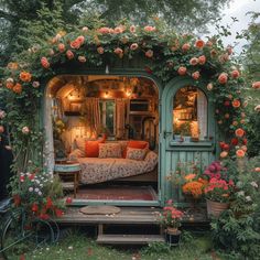 an outdoor living area with couches and flowers growing on the walls, surrounded by greenery