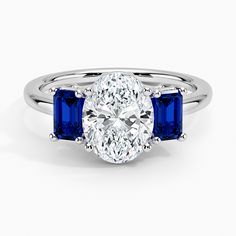 an oval diamond and blue sapphire engagement ring with three stone accents on the band, set in 18k white gold