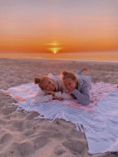 two people laying on a blanket at the beach