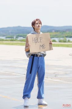 a boy holding a sign that says help me in front of him and looking up at the sky