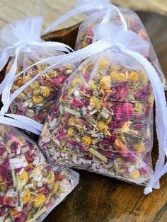 three bags filled with different types of flowers sitting on top of a wooden table next to each other