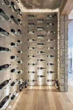 a room filled with lots of wine bottles on the wall next to a wooden floor