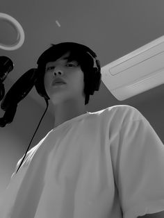 a man with headphones on his ears standing in front of a ceiling fan and air conditioner