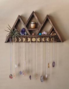 a wooden shelf with various items hanging from it's sides and some air plants on top