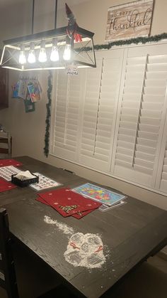 a dining room table is covered in chalk and paper with white shutters on the wall