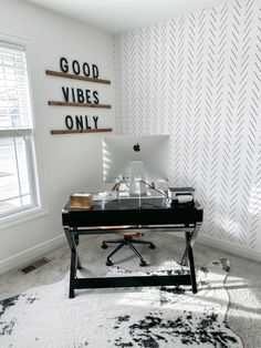 a desk with a computer on top of it in front of a wall that says good vibes only