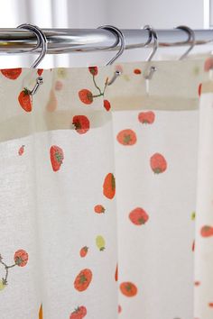 a curtain with red flowers on it hanging from a metal rod