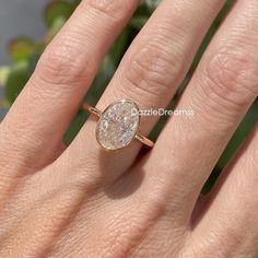 a woman's hand with a ring on it that has an oval shaped diamond in the middle