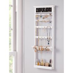 a white wall mounted jewelry rack with lots of necklaces