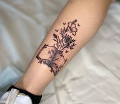 a person with a tattoo on their arm holding a book and flowers in front of them