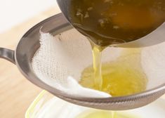 a person pouring oil into a bowl with a strainer