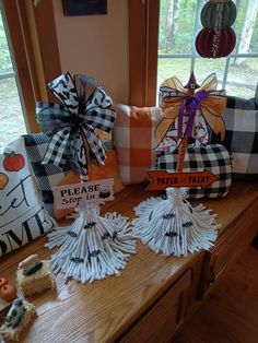 decorative pillows and decorations on a wooden table in front of a window with the words please stay trick that is placed next to them