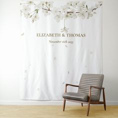 a chair sitting in front of a white curtain with flowers on it and the name elizabeth & thomas