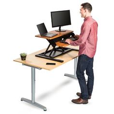 a man standing in front of a computer desk with a monitor and keyboard on it