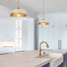 a large kitchen with white cabinets and blue counter tops, two pendant lights over the sink