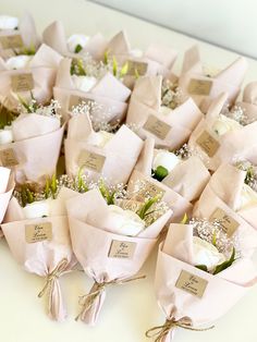 a bunch of flowers are wrapped in pink paper with name tags attached to the stems