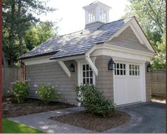 a small gray and white house with a clock tower on top of it's roof