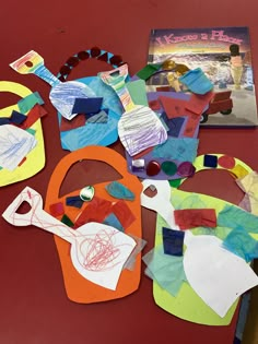 several pieces of paper and crafting materials on a red table with a book in the background