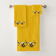 two yellow towels with bees on them hanging from the towel rack in front of a white wall