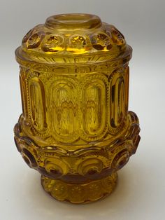 a yellow glass vase sitting on top of a white table