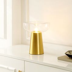 a white table with a gold lamp on it