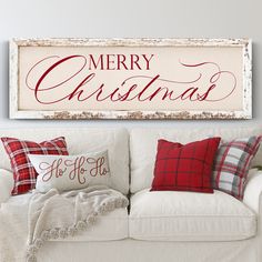 a white couch with christmas pillows on it and a merry sign hanging above the couch