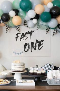 a table topped with cakes and desserts covered in balloons that say fast one on it