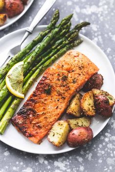 a plate with salmon, potatoes and asparagus on it