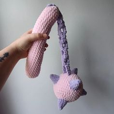 a hand holding a pink and purple toy with an animal on it's tail