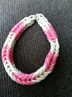 a pink and white braided bracelet sitting on top of a carpet